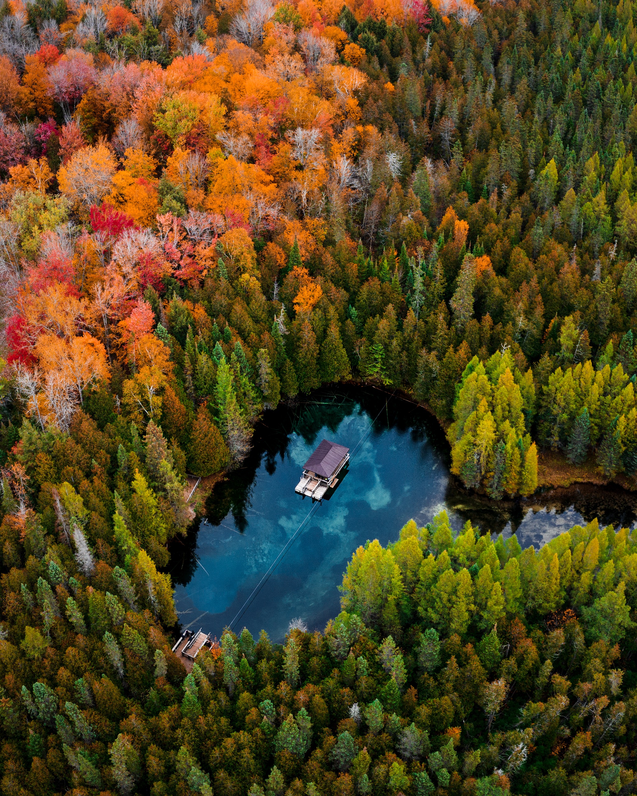 Drone/Aerial image of Kitch-iti-kipi, a freshwater spring in the Upper Peninsula of Michigan. This was taken during a roadtrip in the fall of 2019. The fall colors were starting to change creating a beautiful scene to photograph.